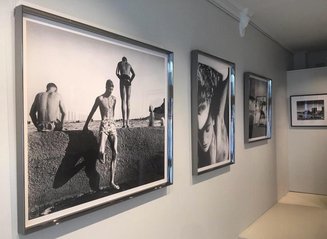 Large black and white photographs framed and hung in a gallery